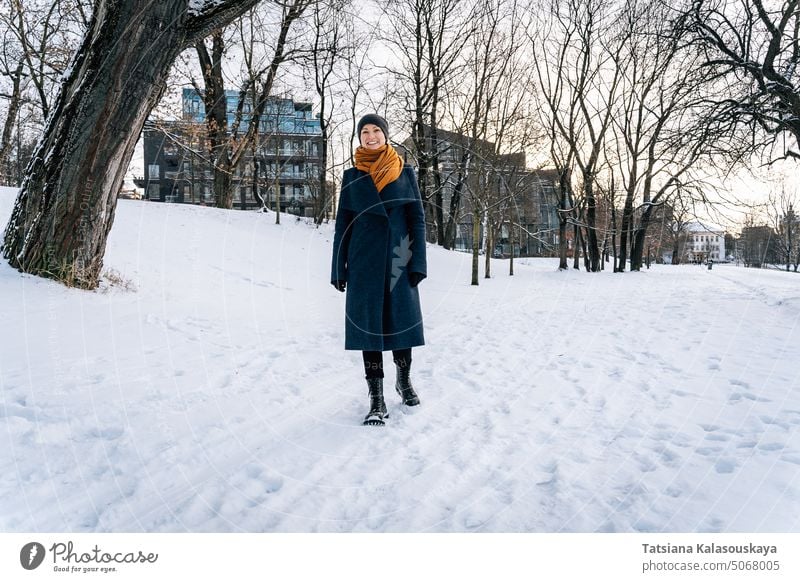 A cheerful young woman walks through a winter city cold snow happiness happy joy female people person adult coat smile one toothy smile Lifestyles Contented