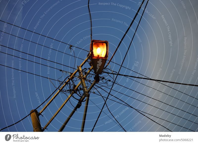 Power lines with street lighting on a line pole in the evening in Adapazari, Sakarya province, Turkey power supply Electricity cross Province Street corner Blue