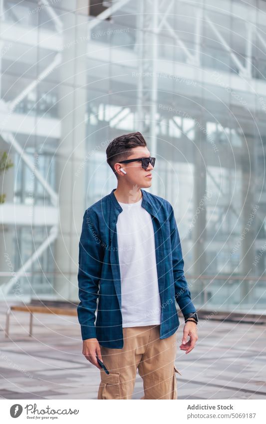 Happy man walking on footbridge street smile urban casual happy building pedestrian male style stroll daytime positive pavement city sunglasses modern glad