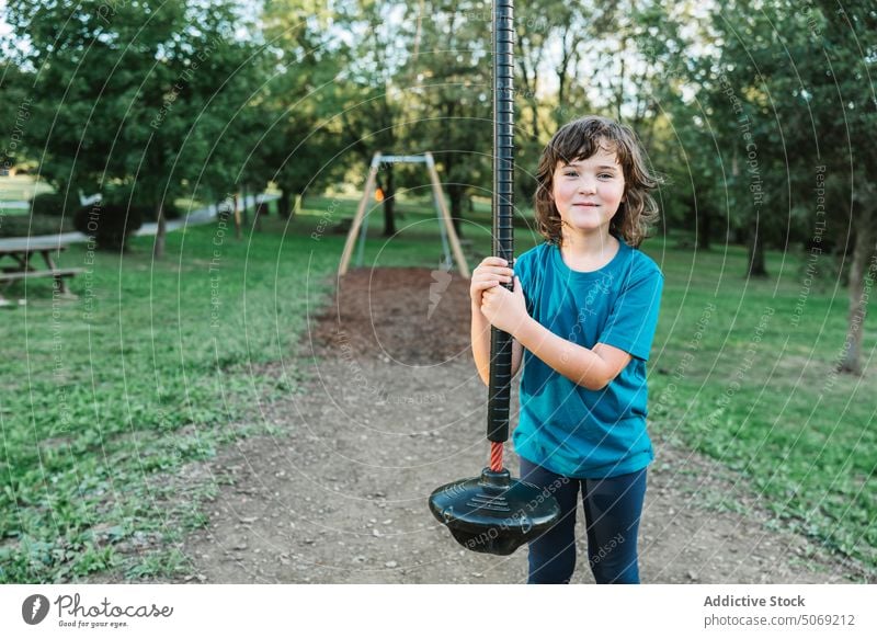 Girl grasping swing rope in park girl happy smile amusement summer portrait positive child cheerful glad activity carefree free time cute adorable optimist