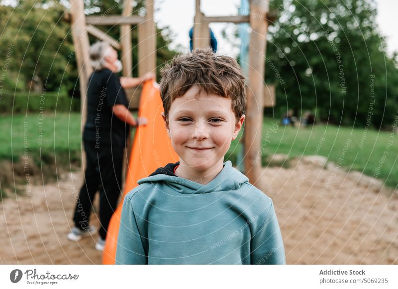 Funny boy playing near grandparent on playground funny cute grandfather grandson playful amusement pastime hoodie glad optimist adorable carefree generation