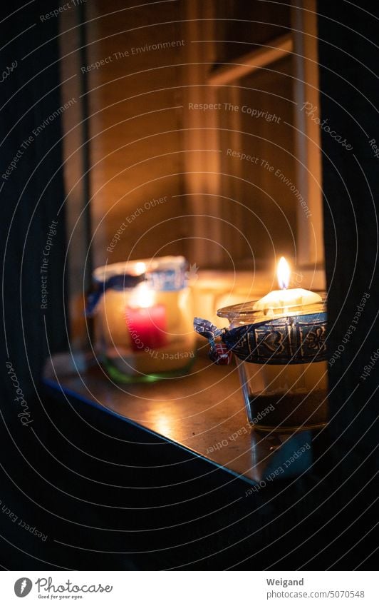 Bright burning candles decorated in glass with jewelry banderole on a windowsill at night Night evening mood candlelight Candlelight Candle in glass