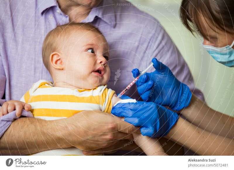 Female nurse with surgical mask and in gloves giving vaccine injection to a baby in clinic. Infant children vaccination. antibiotic arm booster care cry disease