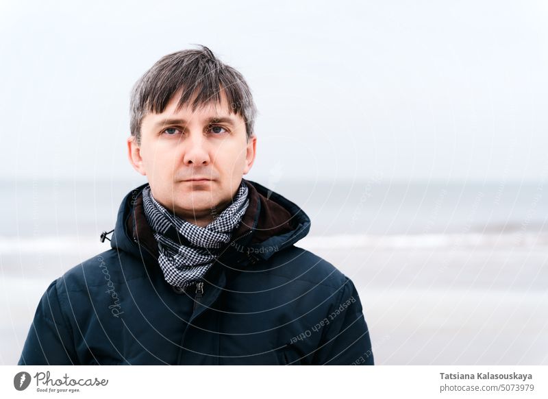 Portrait of a serious relaxed middle-aged man near the winter sea male adult mature 40-50 years 40-45 years dark hair grey hair one alone one person cold frozen