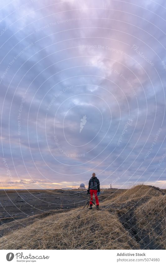 Traveler photographer standing on top of mountain in winter stockness sunset beach photo camera iceland tripod photography man take photo vestrahorn device