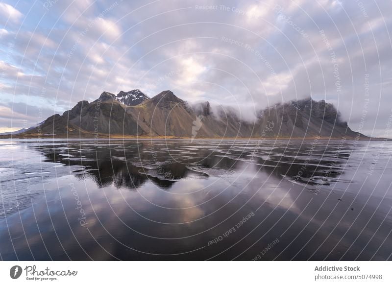 Snowy mountains near frozen lake landscape nordic scenery spectacular Iceland snow Stockness nature cloudy range sky Vestrahorn beach evening winter calm