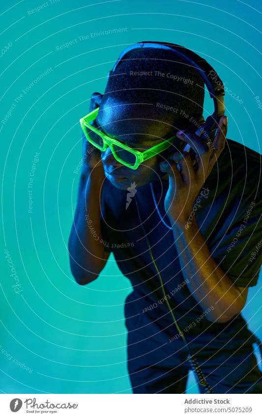 Black DJ in disco goggles checking sound in headphones in nightclub man dj metaverse listen music neon black audio song playlist african american connection