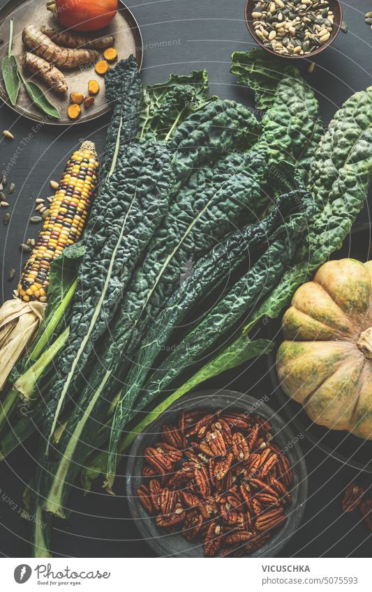 Tuscany kale on kitchen table with ingredients: pumpkin, corn, pecan nuts, herbs and spices . Top view. Healthy cooking preparation tuscany kale top view