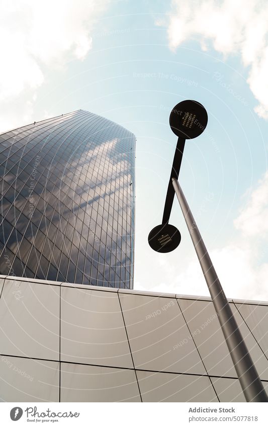 Streetlamp near modern tower building streetlamp skyscraper wall blue sky cloudy daytime tile architecture exterior facade contemporary streetlight metropolis