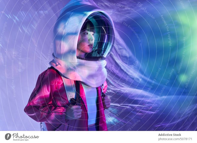 Calm woman in spacesuit helmet in neon light chinese astronaut dream protect cosmonaut concept hide calm emotionless futuristic appearance unemotional backpack