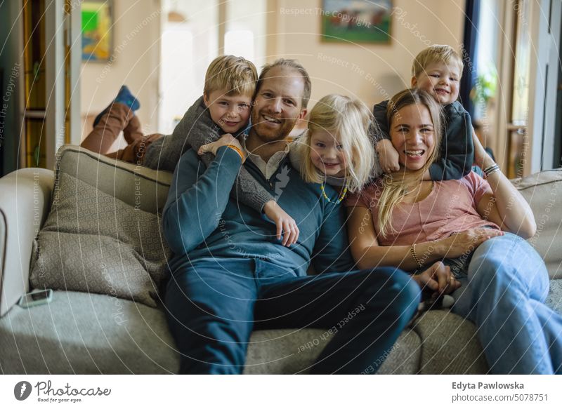 Happy young family sitting on sofa at home real life real people Bonding Family indoors quality time House (Residential Structure) Parenting children enjoyment