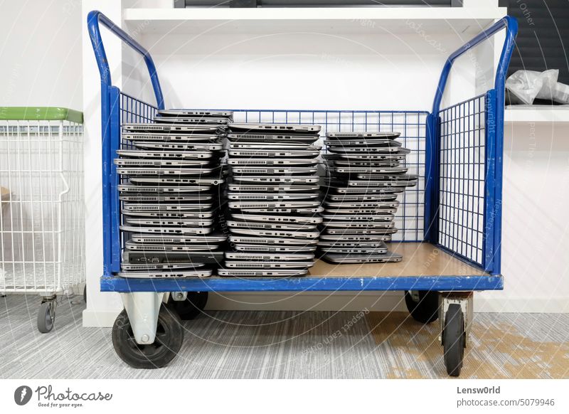 Big stacks of discarded laptops, notebooks on a trolley broken damaged e-waste electrical equipment electronic waste electronics industry environment garbage