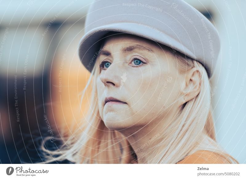 Close up face portrait european middle aged woman with blue green eyes in autumn fashion hat 50s closeup mature elegant pretty female style blonde long hair