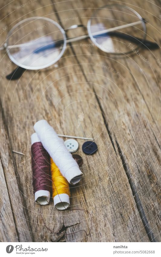 Sewing theme background with brown tones thread and a vintage glasses rustic wood texture vertical pin color colorful multi colored old aged detail sewing