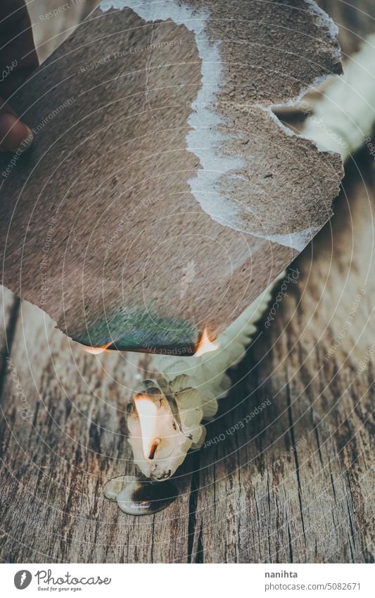 Paper card mockup burning with candle flame against old wood texture background fire note vintage aged craft surface grain romantic close close up detail wax