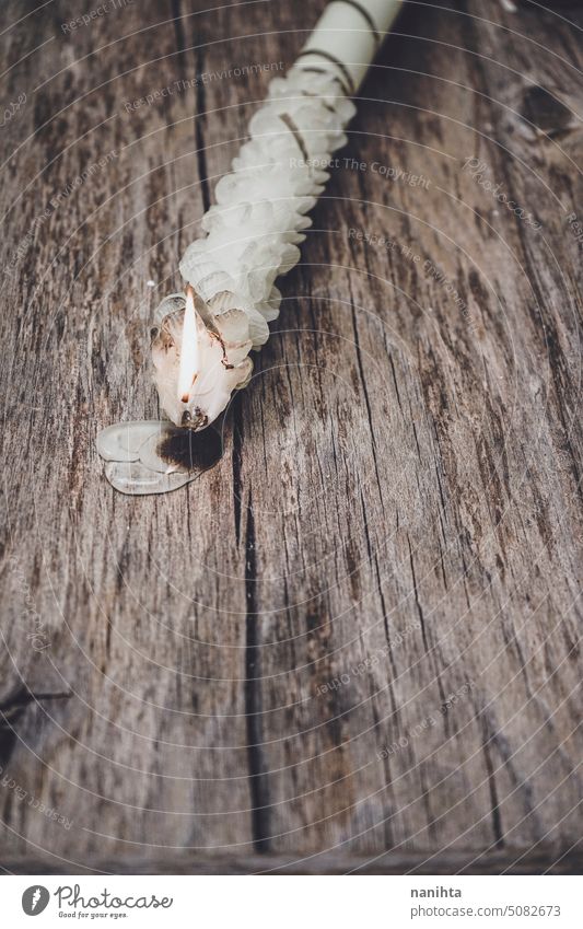 Hand craft white candle with a flame against old wooden background fire vintage aged texture surface grain romantic close close up detail wax delicate fragile