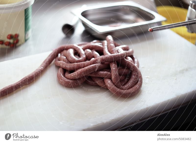 Freshly made sausage snake lying next to a sausage stuffing machine Sausage stuffer Machinery Craft (trade) butcher Butchery Production handicraft production