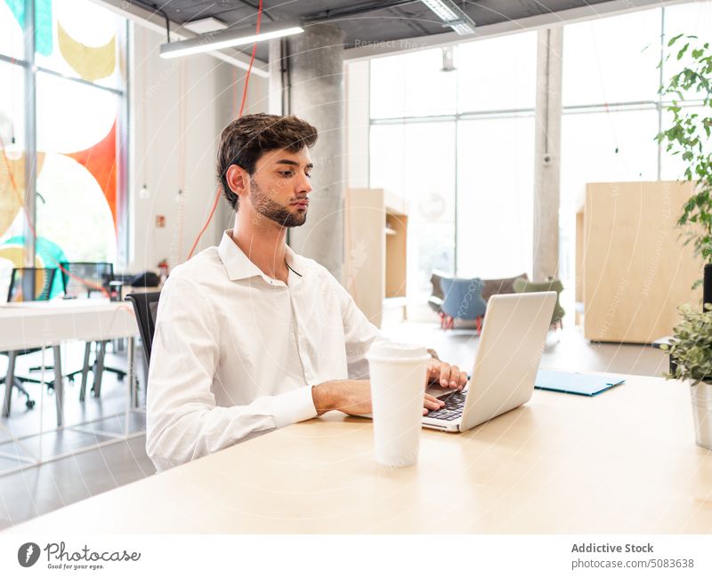 Focused man working on laptop in coworking space concentrate using browsing cafeteria gadget office surfing device internet computer job serious table male