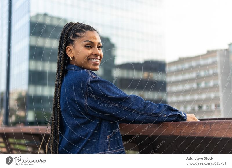 Cheerful black woman standing on bridge against urban traffic railing town cityscape building chill street smile positive happy african american ethnic female