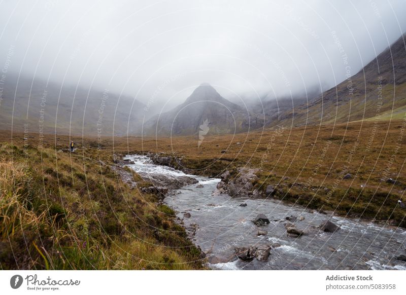 Scenic landscape of mountains under cloudy sky person range mist fog flow stream highland picturesque scotland europe uk united kingdom grass nature hill ridge