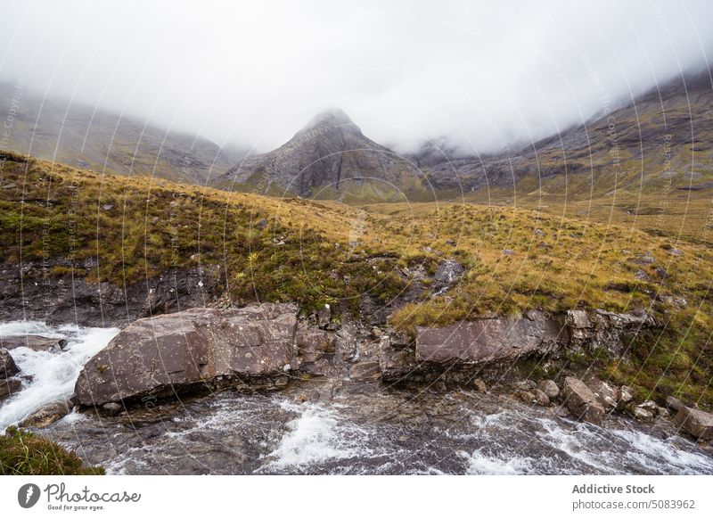 Scenic landscape of mountains under cloudy sky range mist fog flow stream highland picturesque scotland europe uk united kingdom grass nature hill ridge water