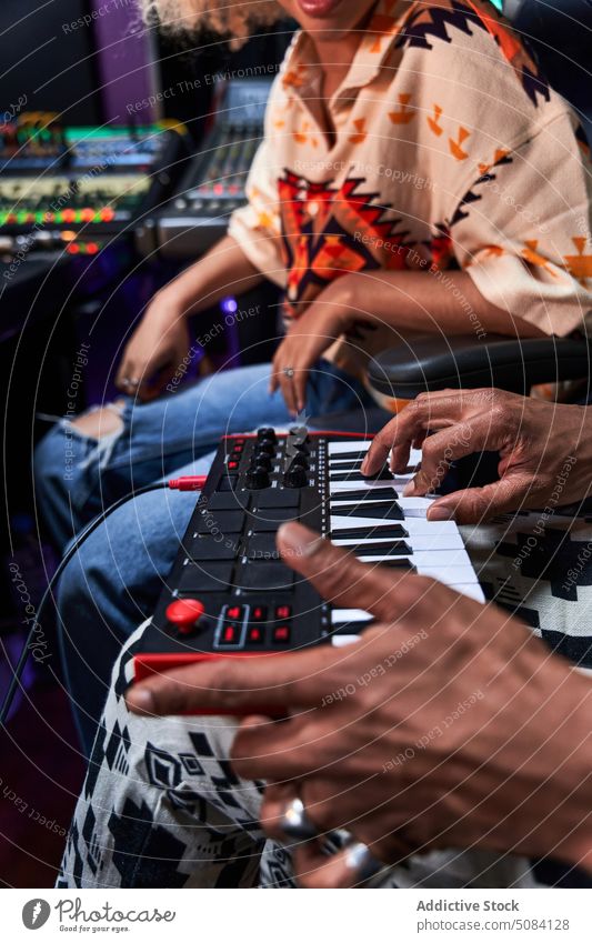 Anonymous black man playing synthesizer while female watching in recording studio music hobby woman enjoy rehearsal mixer song melody equipment practice