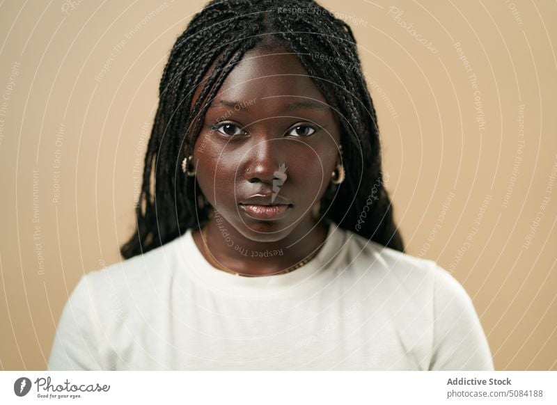 Calm black woman looking at camera model portrait afro braids appearance personality studio beige background human face calm female lady young african american