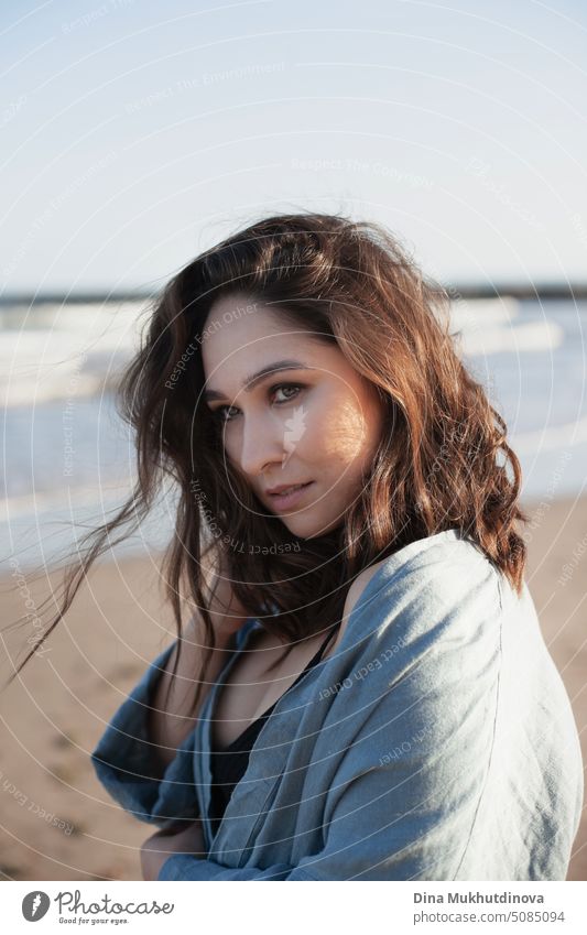 Portrait of beautiful caucasian woman with brown hair at the beach by the sea looking away. Romantic portrait of attractive woman. Book cover. deep in thought