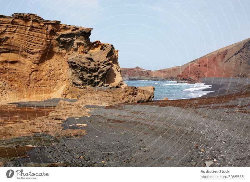 Rocky cliff in foamy ocean on sunny day mountain volcanic landscape nature seascape scenic picturesque breathtaking untouched island formation rocky geology