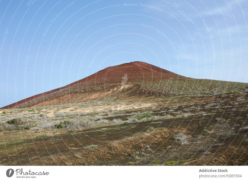 Arid terrain and volcanic mountain under blue sky landscape island volcano nature sand arid scenery travel range wild picturesque scenic formation hill geology