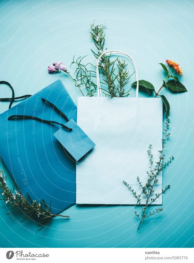 Seasonal mockup of a blue paper gift bag surrounded by flowers in flat lay format background spring nature natural organic wild floral decor bouquet herbs