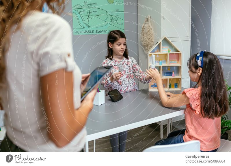 Student showing incandescent light bulb and led lamp in ecology classroom female student giving classmate girl sustainable efficiency illumination fluorescent