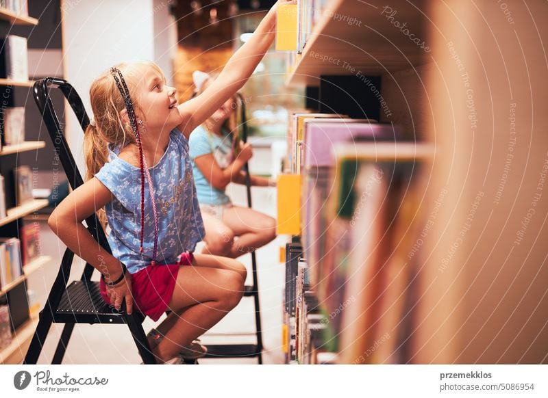 Schoolgirls looking for books in school library. Students choosing books. Elementary education. Doing homework. Back to school back schoolgirl child reading