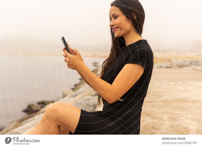 Sportswoman using smartphone near sea with fog selfie break social media workout rest sporty positive smile fit sportswoman athlete harmony mist warm up fitness