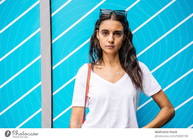 Woman with dark long hair near blue wall with stripes glancing woman glance colorful millennial bright confident individuality appearance geometry female young