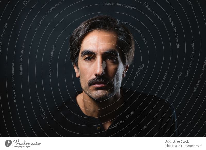 Serious man with mustache on black background portrait serious masculine individuality personality studio shot emotionless unshaven male adult appearance