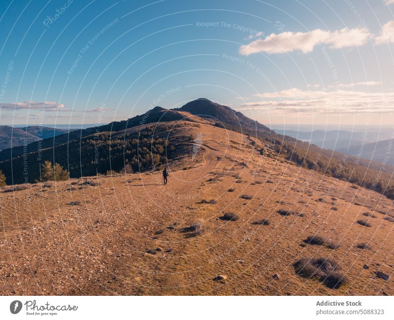 Hiker walking on ridge top in sunlight mountain range trekking landscape nature traveler path tourism scenery explore hike wanderlust puerto de la puebla