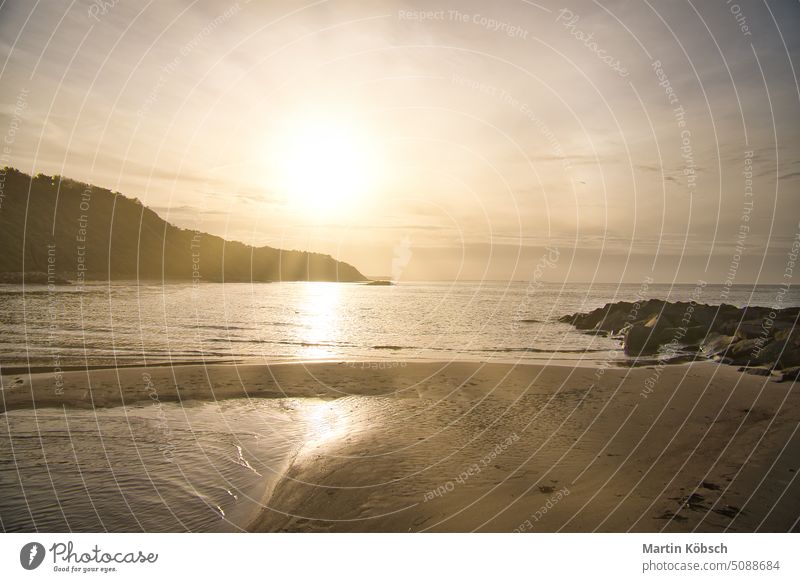 Sunset on the Danish coast. Beach, waves. Hill with trees in background. Landscape Hundested Denmark vacation destination sunbeam evening hour travel clouds sky