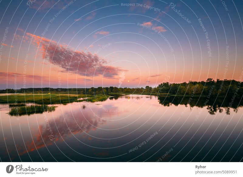 River Landscape In Belarus Or European Part Of Russia In Sunset Time Of Summer Evening. Moon Rising Over Water Lake Or River. Nature At Sunny Evening. europe