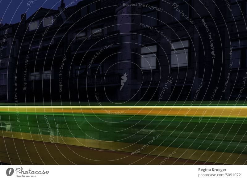 Green-yellow streetcar makes a luminous trail through the canyon of houses at night Train Track Train travel Rail transport Means of transport Public transit