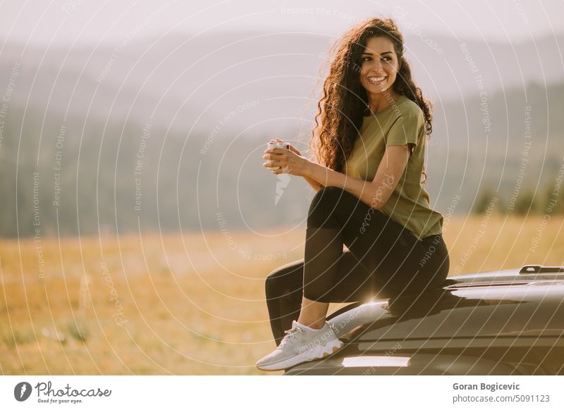 Young woman relaxing on a terrain vehicle hood at countryside auto young caucasian holiday summer trip car vacation female lifestyle outdoors person adult