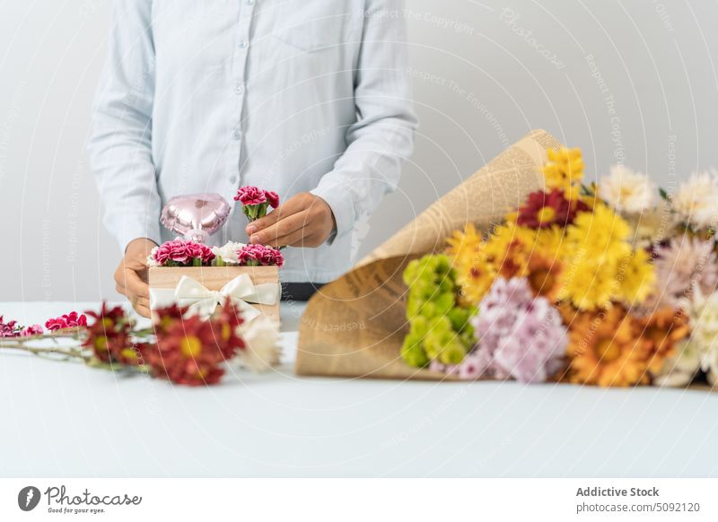 Crop woman arranging flowers in box florist arrange carnation bouquet bow present creative floral floristry small business order romantic female festive event