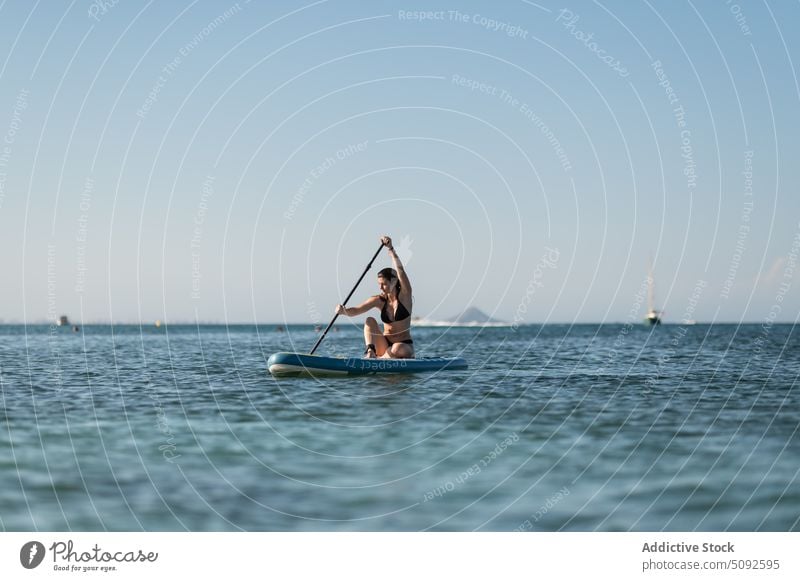 Tourist rowing while floating on sup board in sea tourist paddleboard ripple water tranquil cloudless woman sky hobby nature summer ride recreation endless