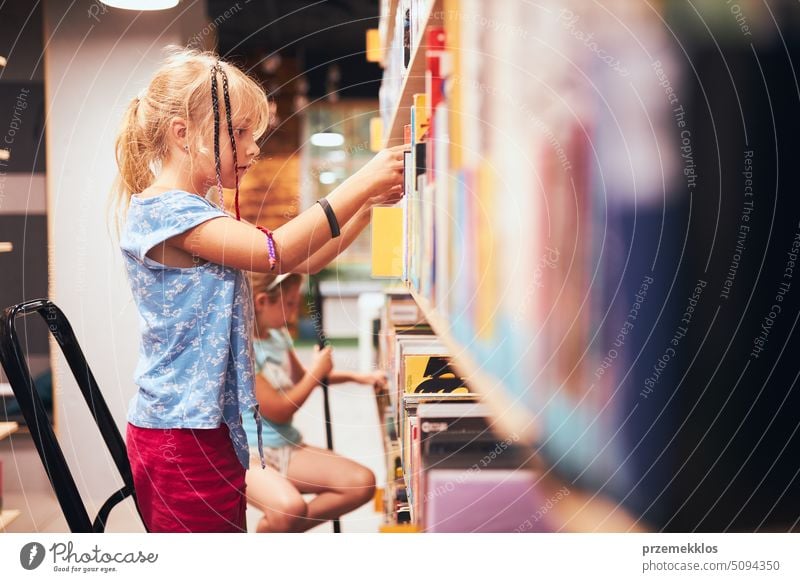 Schoolgirls looking for books in school library. Students choosing books. Elementary education. Doing homework. Back to school back schoolgirl child reading