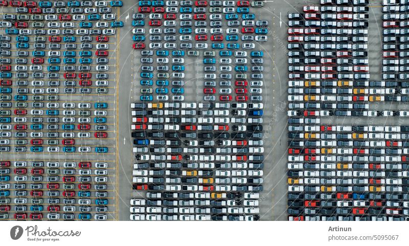 Aerial view of new cars stock at factory parking lot. Above view cars parked in a row. Automotive industry. Logistics business. Import or export new cars at warehouse. Big parking lot at port terminal