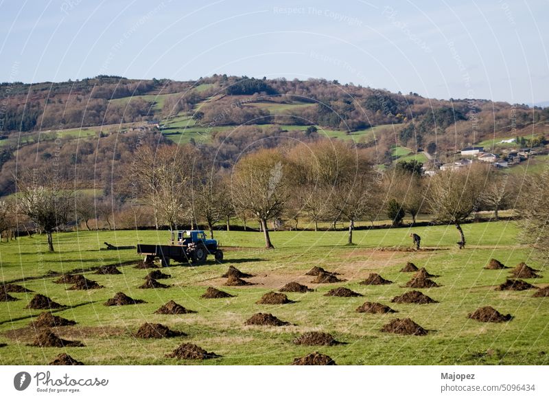 Beautiful rural landscape in north of spain. Unrecognizable person fertilizing unrecognizable person hill forest environment farm field village day scenery