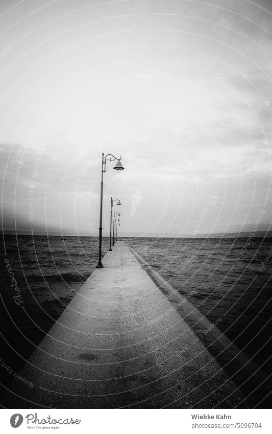 Dull and cloudy view of the sea from a concrete jetty with lanterns Europe Saloniki Greece Vacation and travel Ocean Gray Fog Moody cloudy weather cloudy day