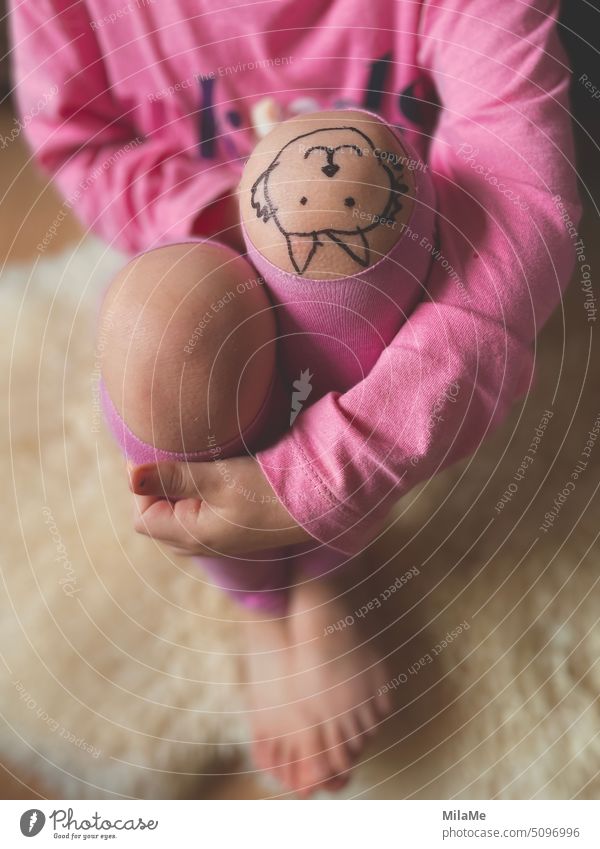 Sitting child with leggings with holes looks at her painted picture on knee creatively Painting (action, artwork) Skin Child Infancy be a child fun Allow