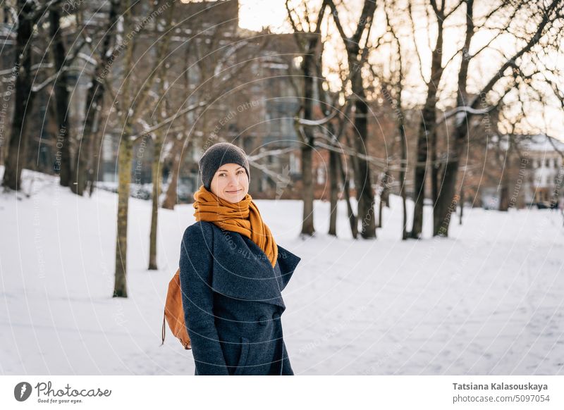 A woman in warm winter clothes looks into the camera and smiles in winter cold snow happiness happy joy female people person adult coat cheerful One Woman Only