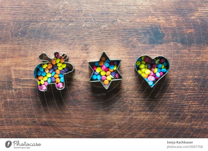 Cookie cutters filled with colorful sugar beads on a brown wooden table. Christmas. cookie cutter Sugar perl Christmas & Advent Christmas biscuit Preparation